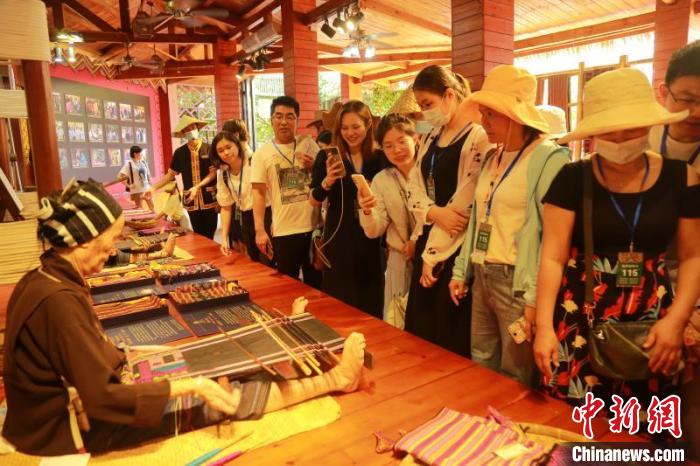 图为黎族阿婆在海南槟榔谷黎苗文化旅游区内向游客展示黎锦技艺。潘达强摄